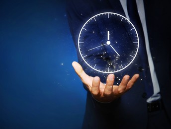 Businessman holding virtual clock on dark background, closeup. Space for text