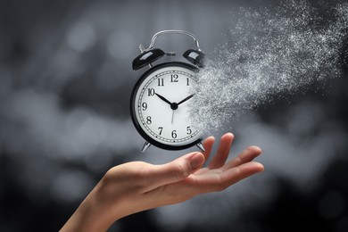 Time running out. Woman with dissolving alarm clock on blurred background, closeup
