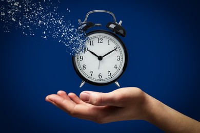 Time running out. Woman with dissolving alarm clock on blue background, closeup