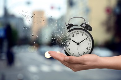 Time running out. Woman with dissolving alarm clock on blurred background, closeup