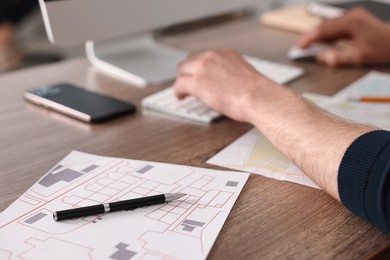 Photo of Cartographer working with cadastral maps at wooden table in office, closeup