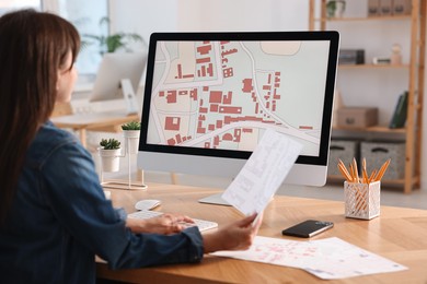 Cartographer working with cadastral maps at table in office