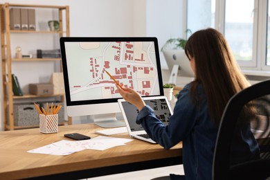 Cartographer working with cadastral maps at table in office