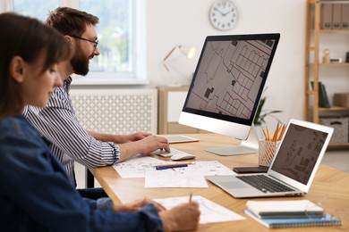 Cartographers working with cadastral maps at table in office