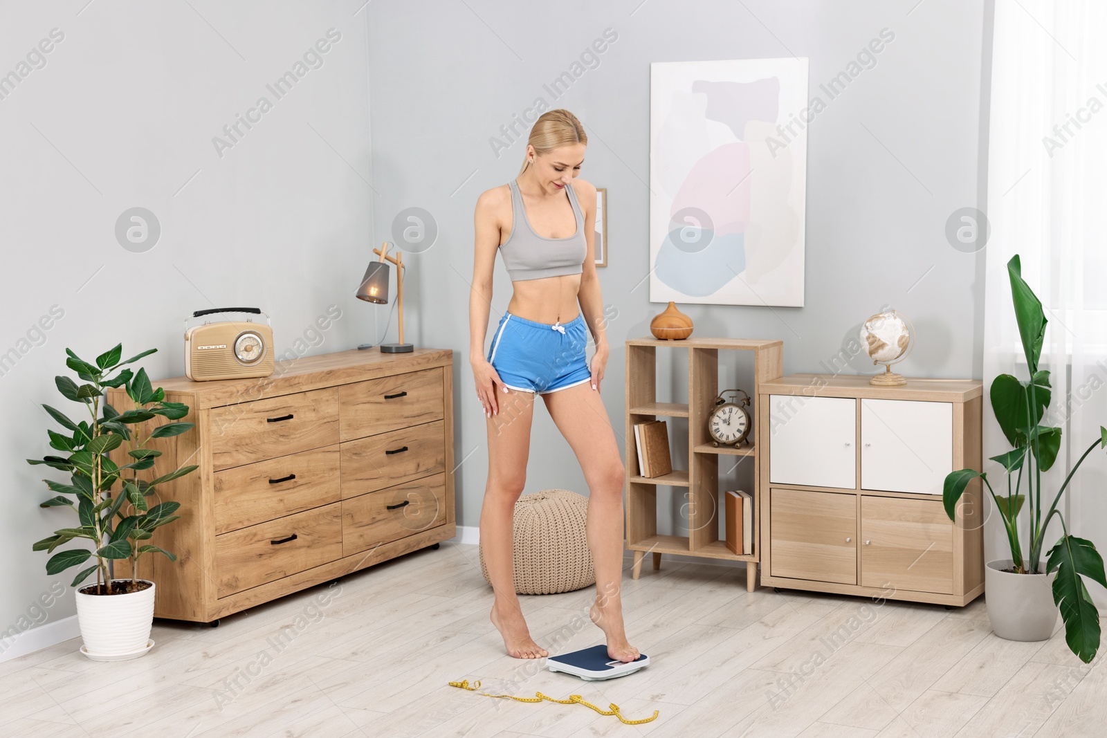 Photo of Woman stepping on floor scale at home