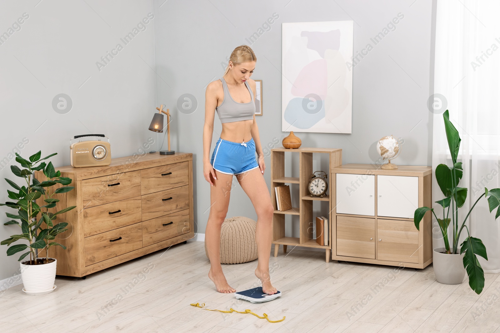 Photo of Woman stepping on floor scale at home