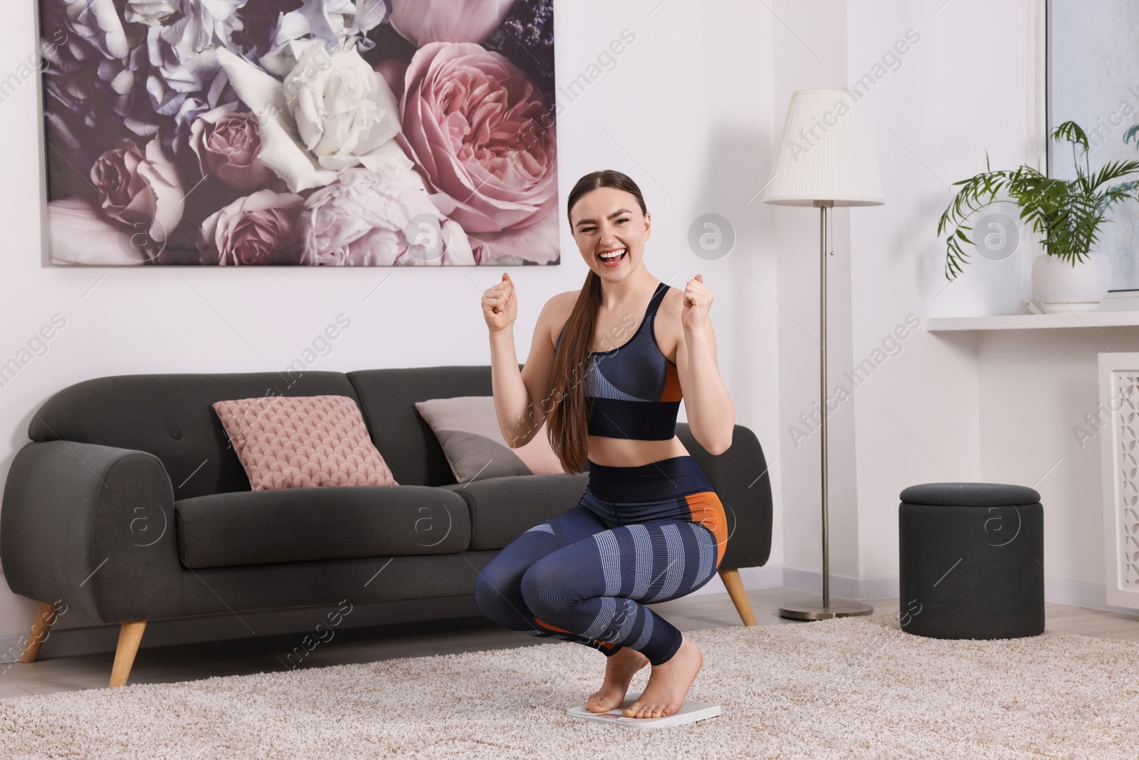 Photo of Happy woman on floor scale at home