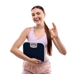 Happy woman with floor scale showing ok gesture on white background