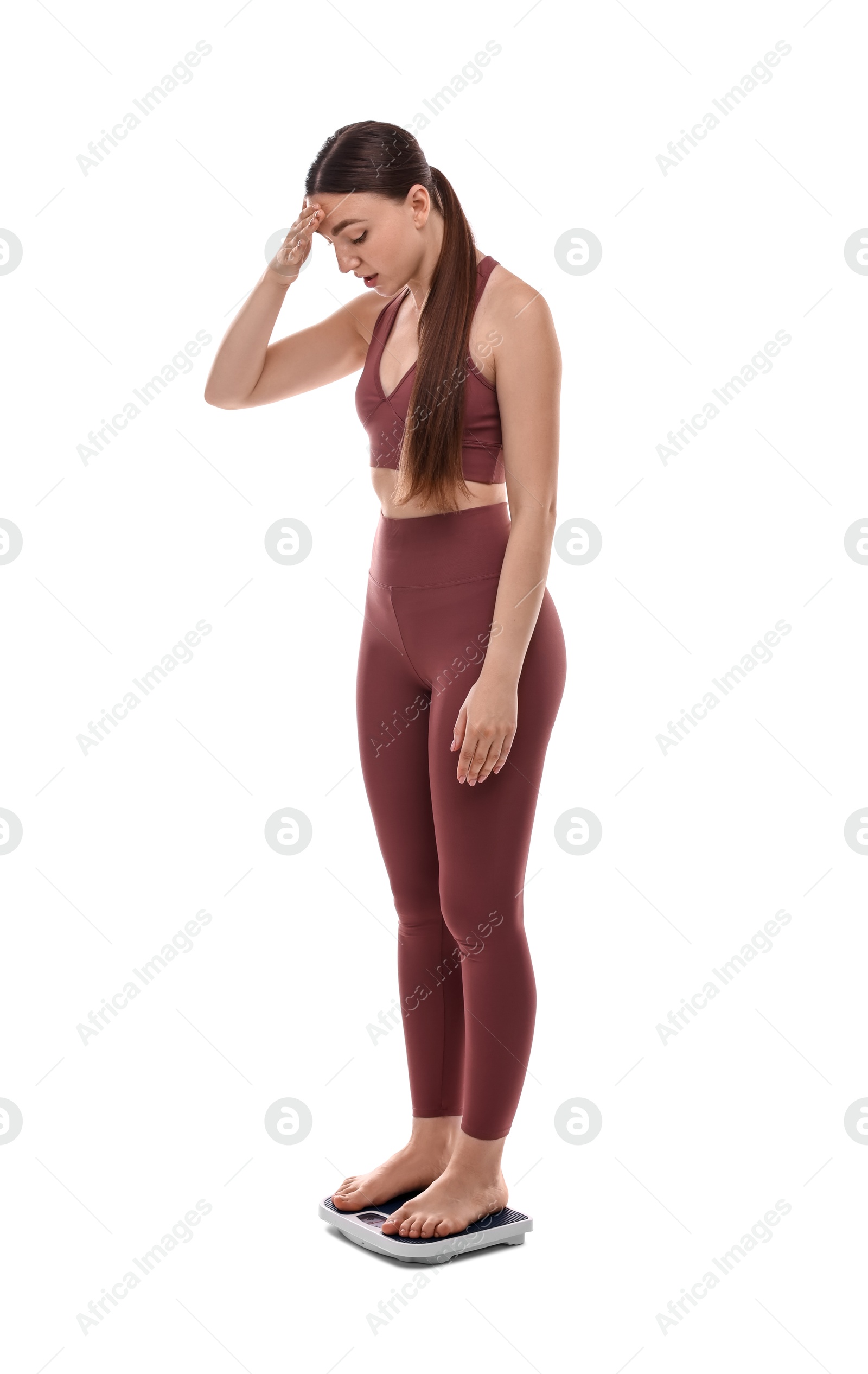 Photo of Worried woman standing on floor scale against white background