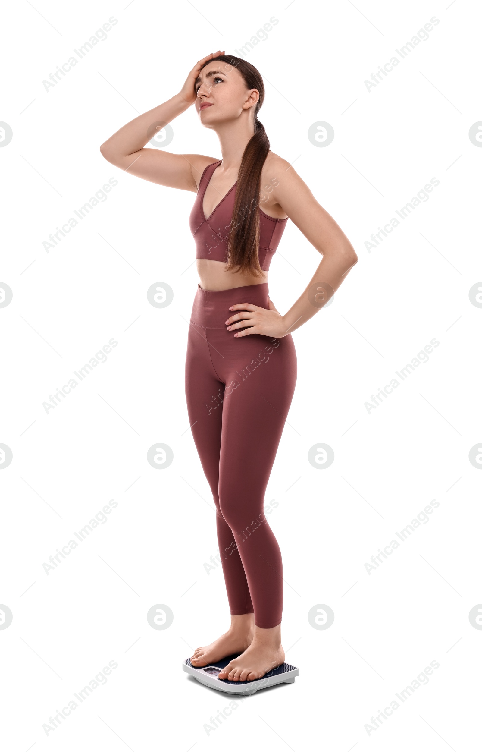 Photo of Worried woman standing on floor scale against white background