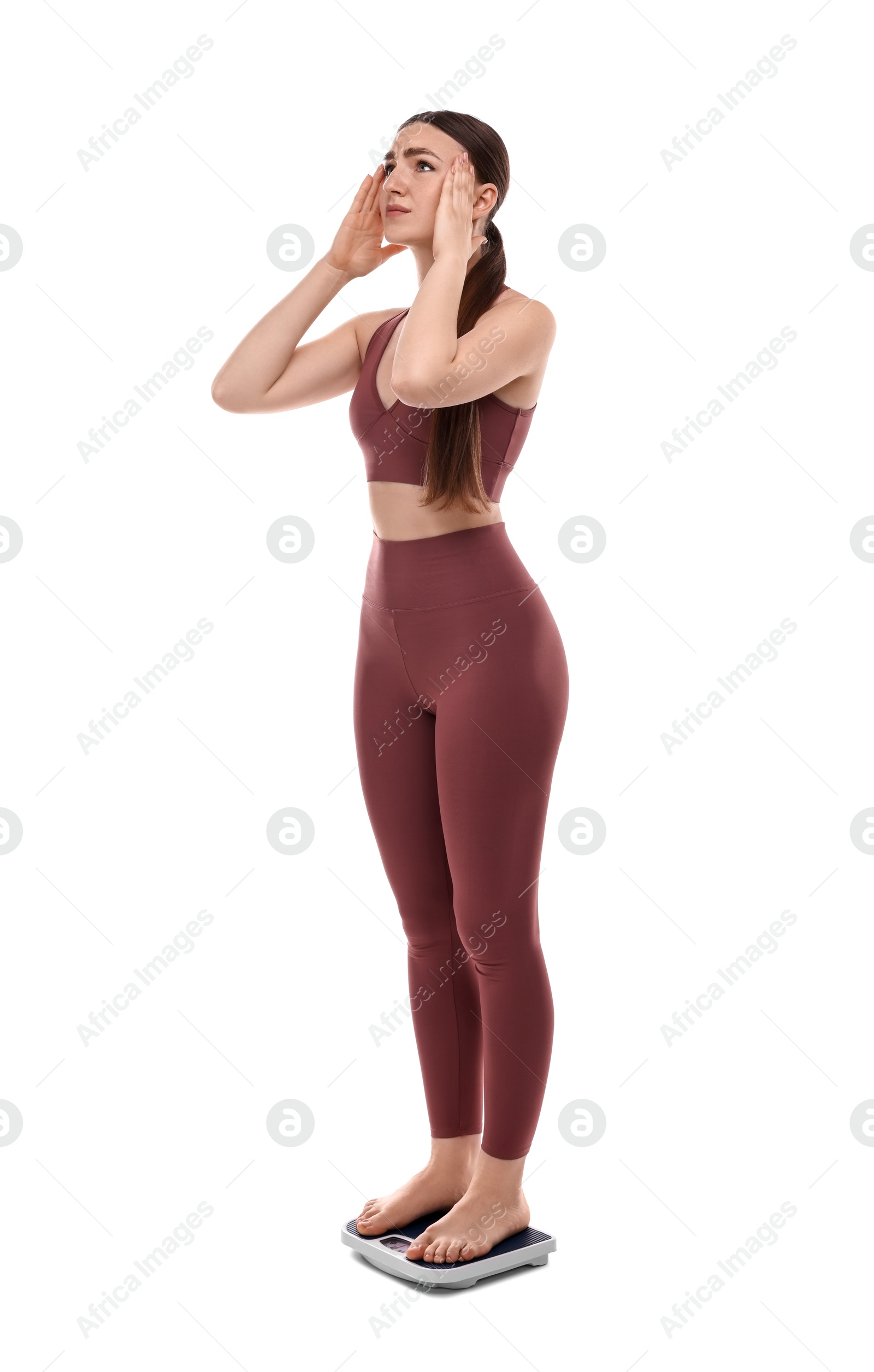 Photo of Worried woman standing on floor scale against white background