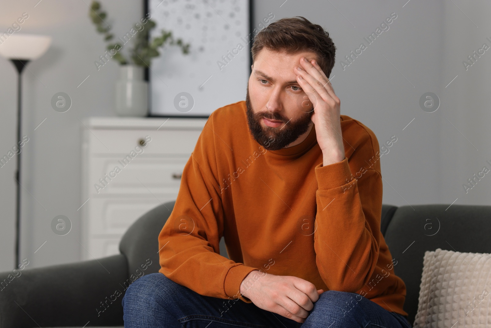 Photo of Overwhelmed man sitting on sofa at home