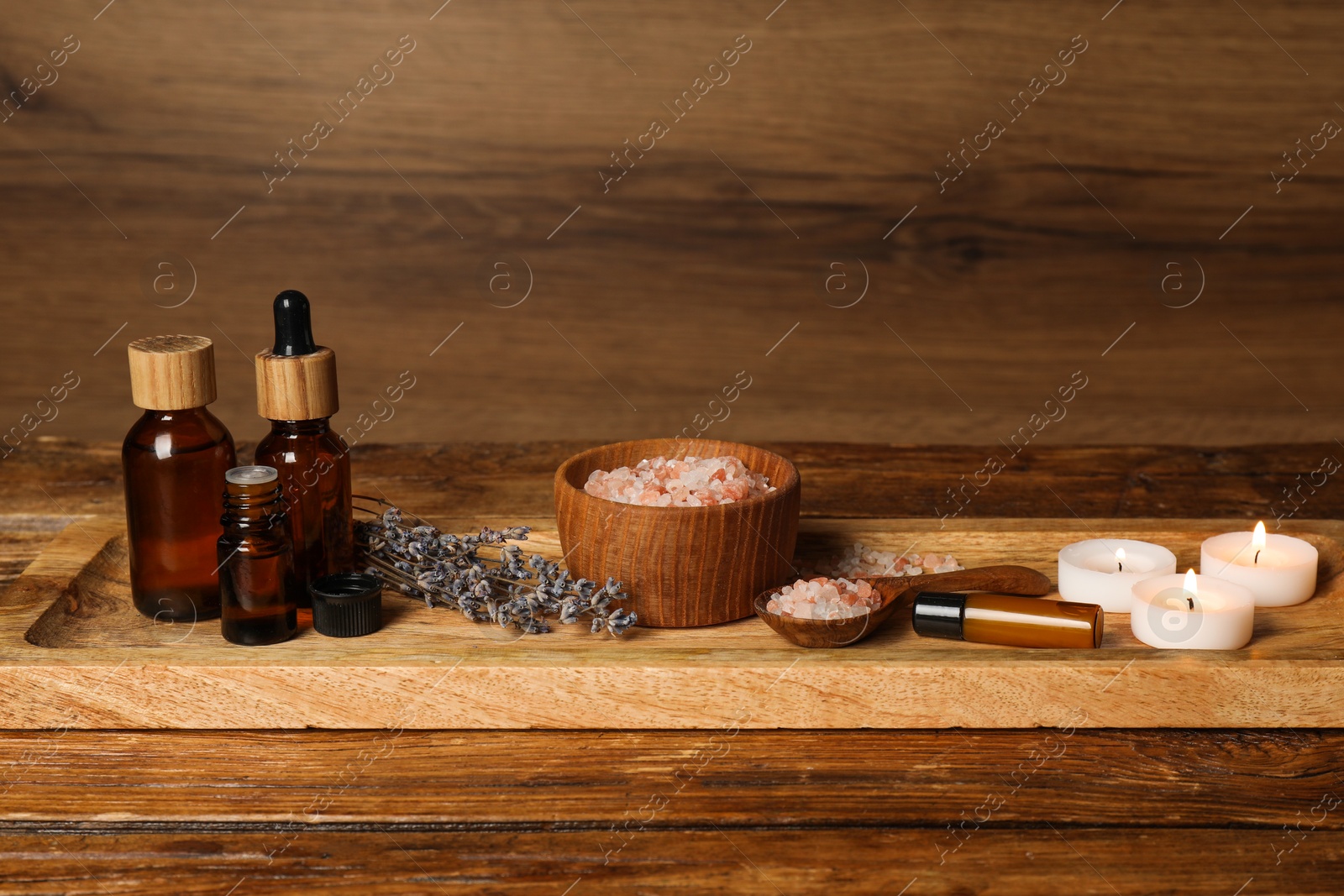 Photo of Different aromatherapy products and burning candles on wooden table