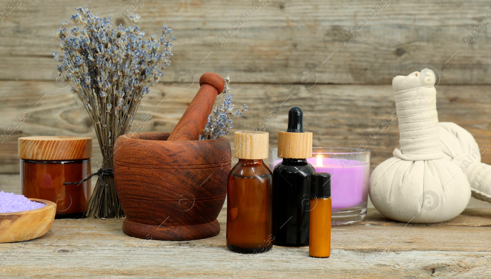 Photo of Different aromatherapy products, burning candle and lavender on wooden table