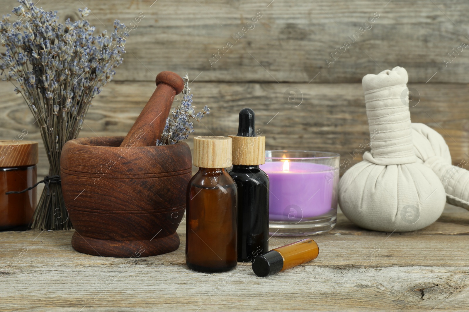 Photo of Different aromatherapy products, burning candle and lavender on wooden table