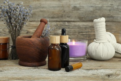 Different aromatherapy products, burning candle and lavender on wooden table