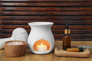 Photo of Different aromatherapy products and burning candle on wooden table