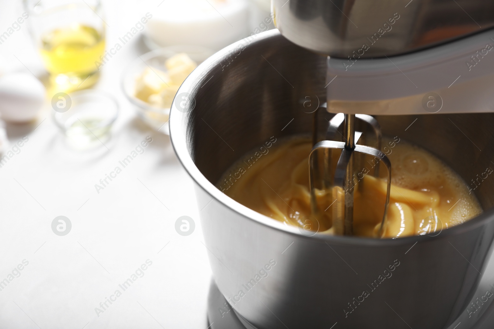 Photo of Making dough in bowl of stand mixer on white table. Space for text