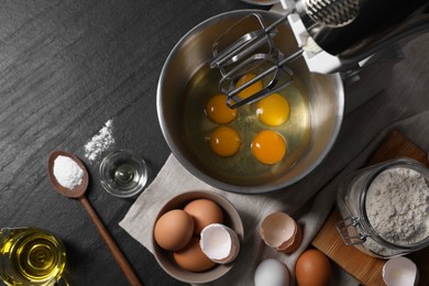 Making dough. Raw eggs in bowl of stand mixer and ingredients on black table, flat lay
