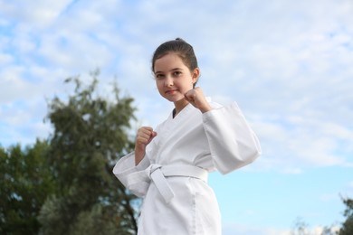 Photo of Cute little girl in kimono training karate outdoors