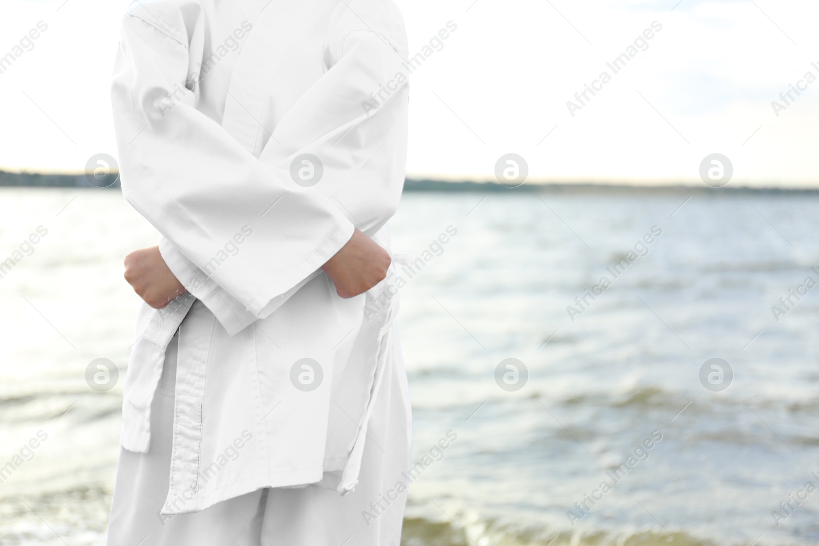 Photo of Cute little girl in kimono near river, closeup. Karate practicing