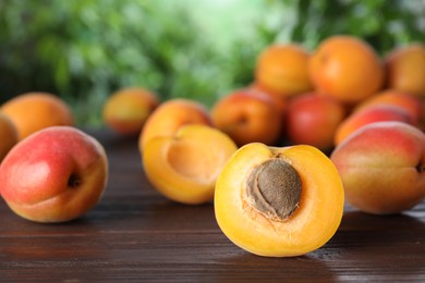 Photo of Many fresh ripe apricots on wooden table against blurred background