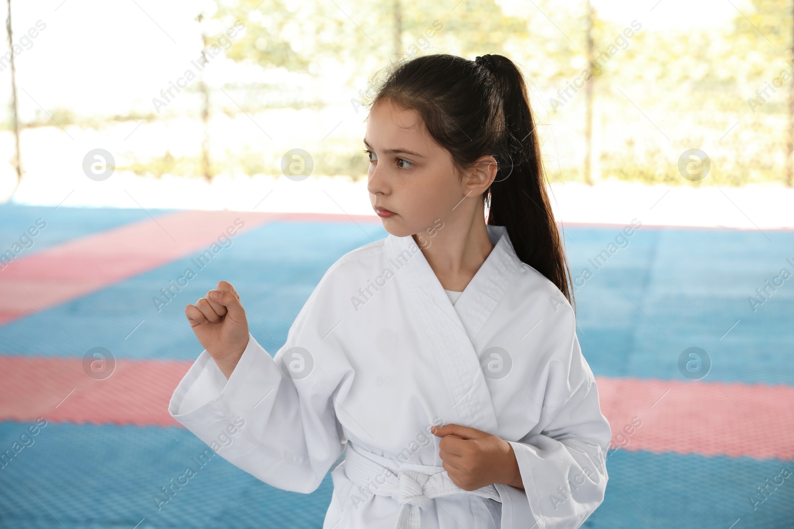 Photo of Girl in kimono practicing karate on tatami outdoors