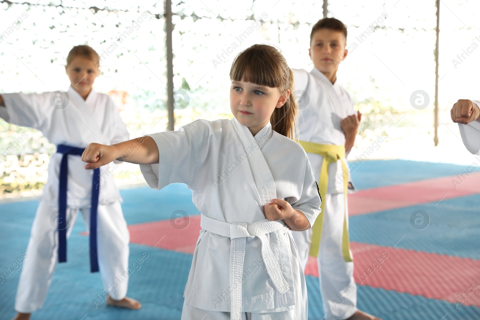 Photo of Children in kimono practicing karate on tatami outdoors