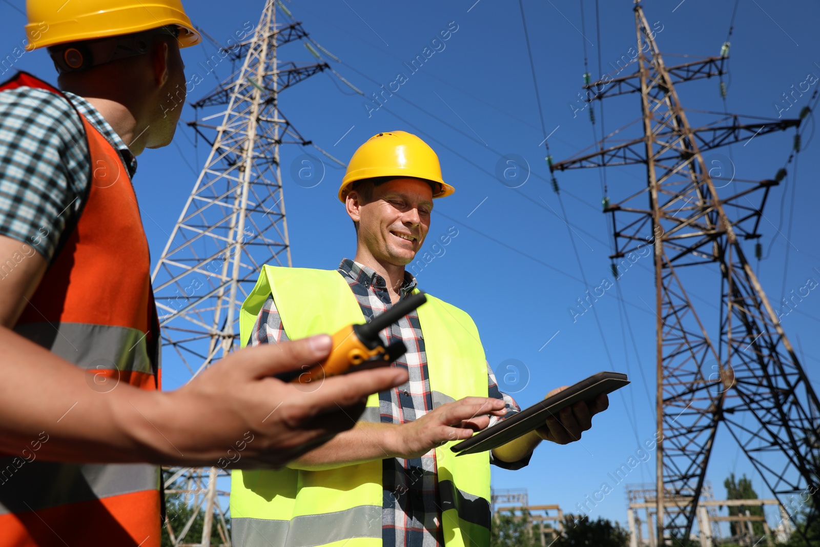 Photo of Professional electricians in uniforms near high voltage towers