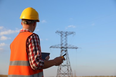Photo of Electrical engineer with walkie talkie near high voltage tower