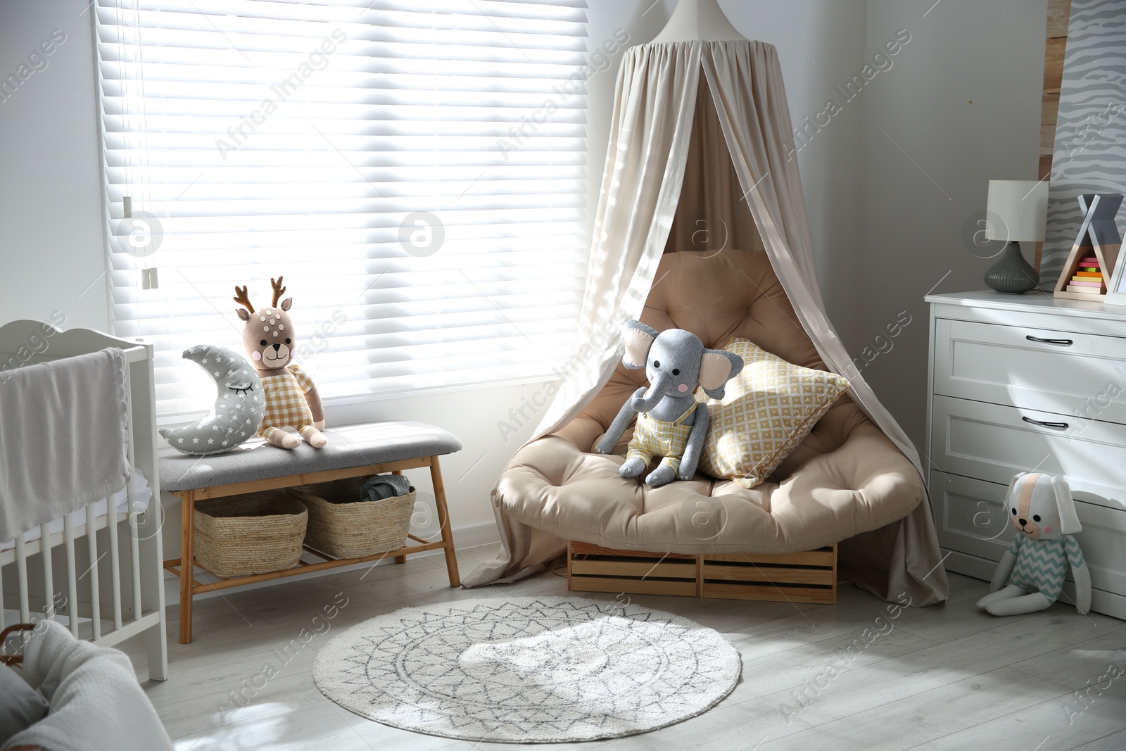 Photo of Beautiful baby room interior with comfortable armchair and bench near window