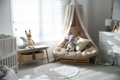 Beautiful baby room interior with comfortable armchair and bench near window