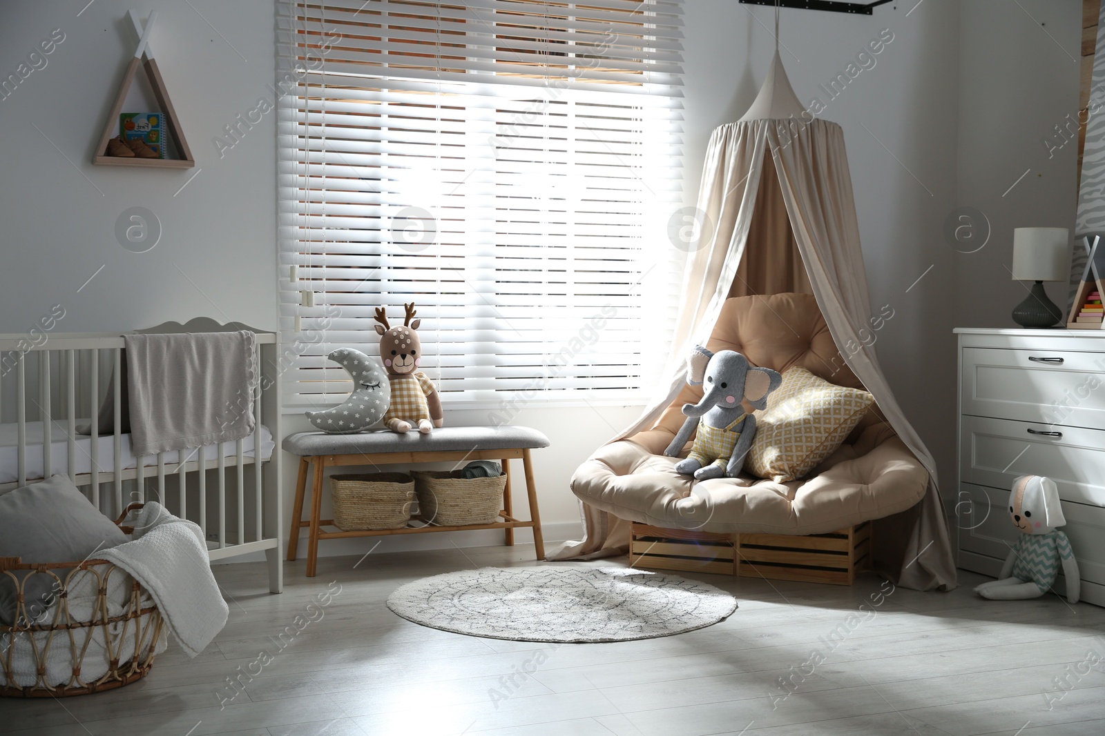 Photo of Beautiful baby room interior with comfortable armchair and bench near window