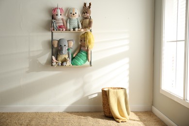 Shelf with cute toys on light wall indoors. Baby room interior element