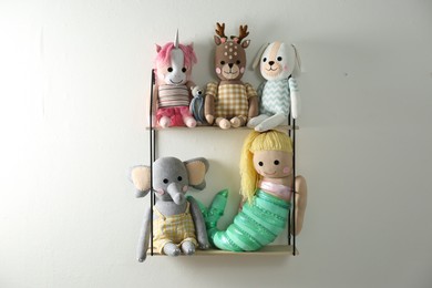 Photo of Shelf with cute toys on light wall. Baby room interior element