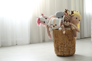 Photo of Funny stuffed toys in basket on floor, space for text. Children's room interior decor