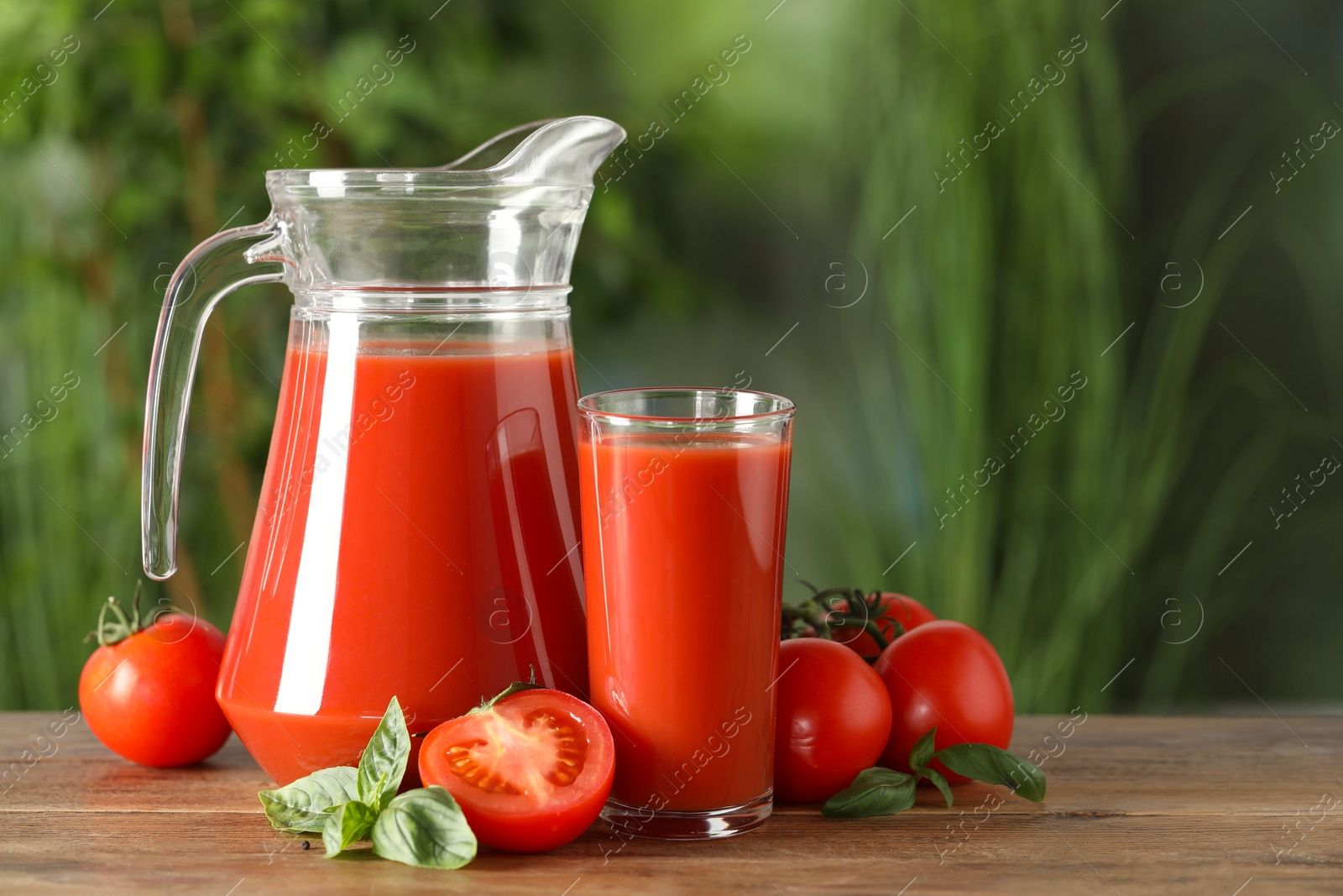 Photo of Tasty tomato juice, basil and fresh vegetables on wooden table outdoors. Space for text