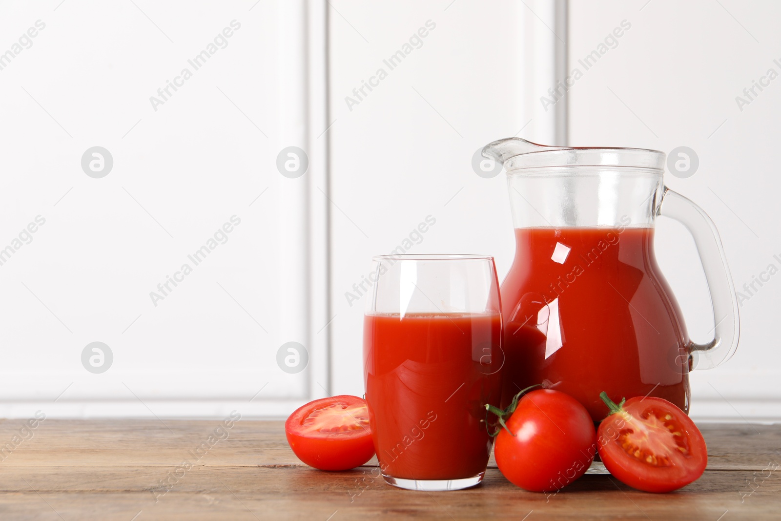 Photo of Tasty tomato juice and fresh vegetables on wooden table, space for text