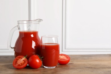 Photo of Tasty tomato juice and fresh vegetables on wooden table, space for text