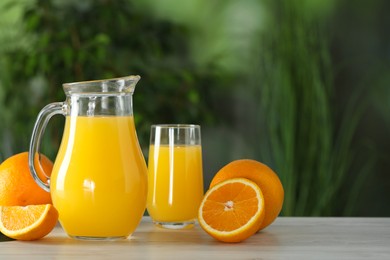 Photo of Tasty orange juice and fresh fruits on white wooden table outdoors. Space for text