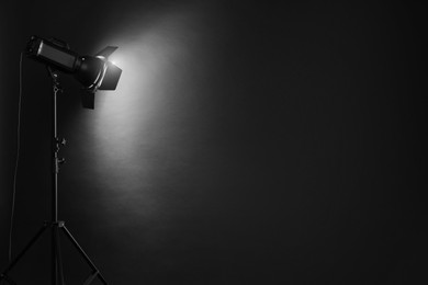 Photo of Dark photo background and professional lighting equipment in studio. Space for text