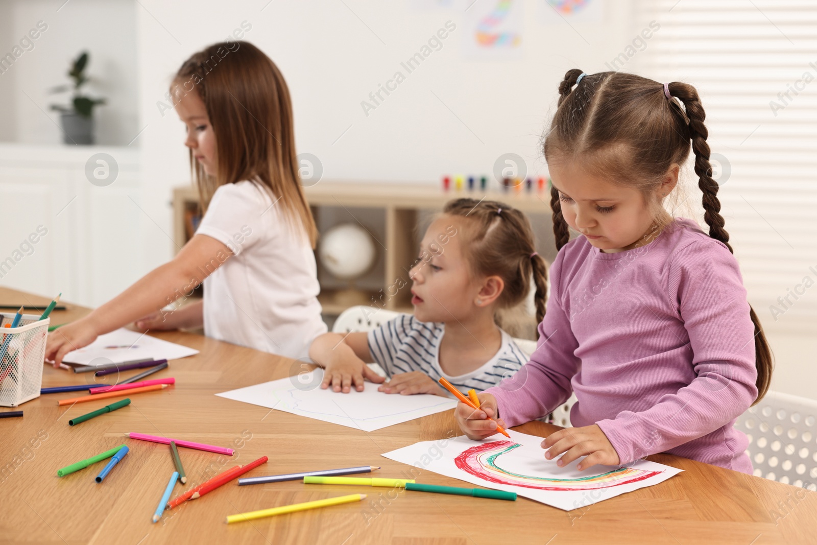 Photo of Cute little children drawing at wooden table indoors