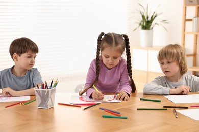 Photo of Cute little children drawing at wooden table indoors