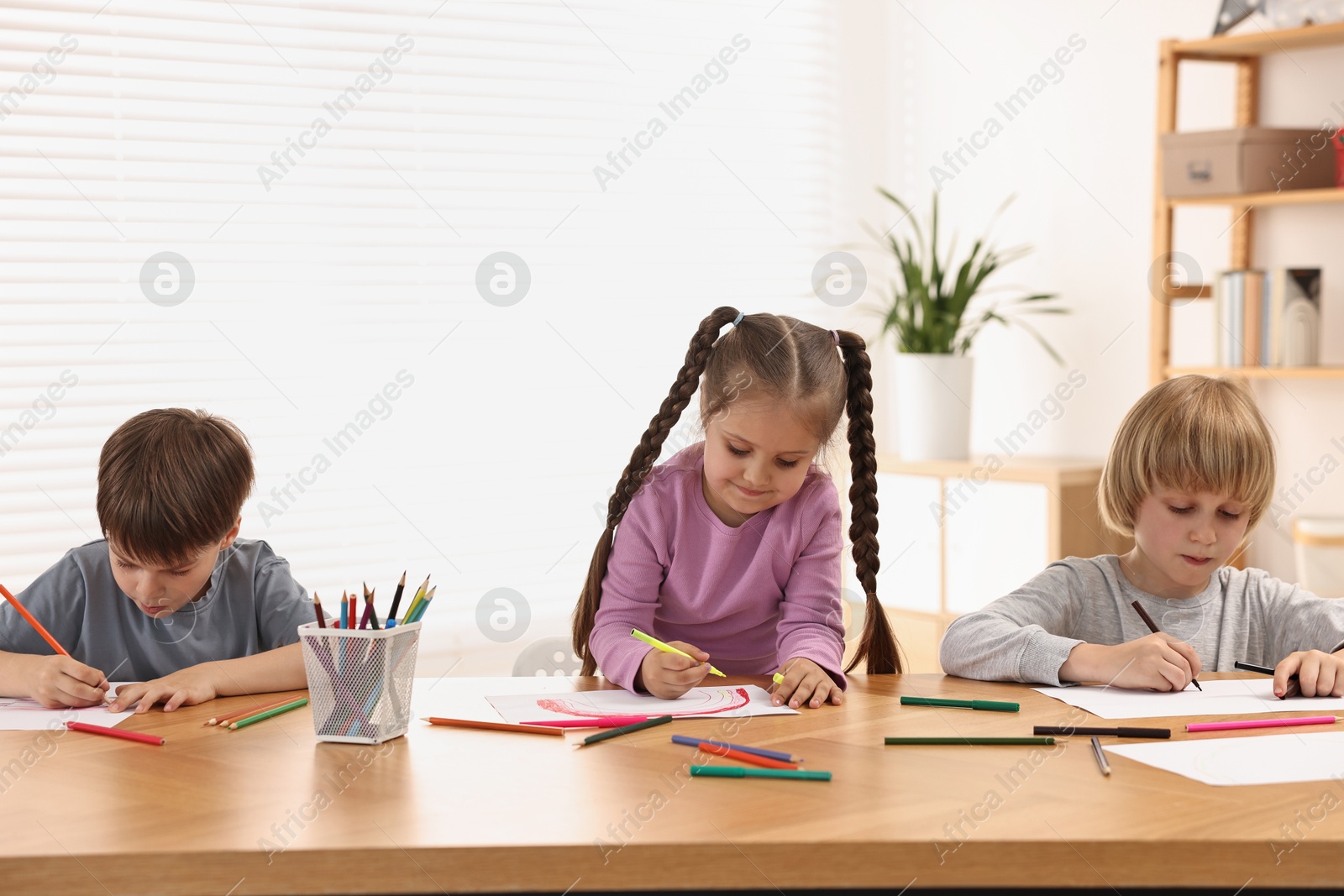 Photo of Cute little children drawing at wooden table indoors