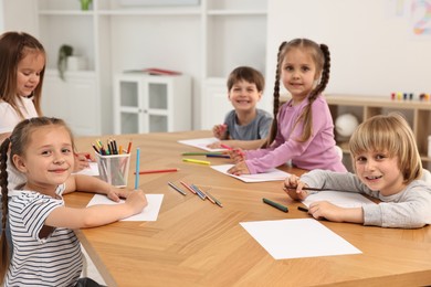 Group of children drawing at wooden table indoors