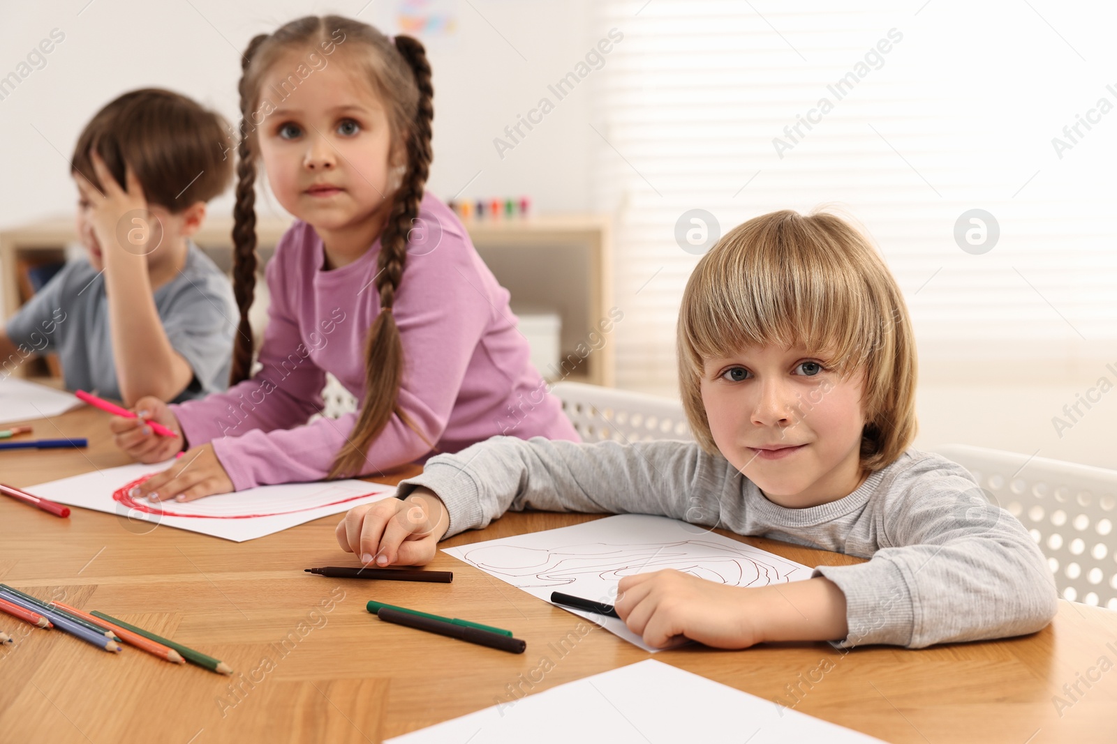 Photo of Cute little children drawing at wooden table indoors