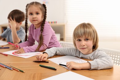 Photo of Cute little children drawing at wooden table indoors
