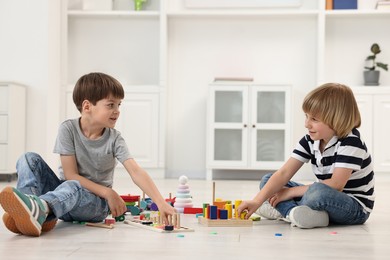 Cute little children playing together on floor indoors