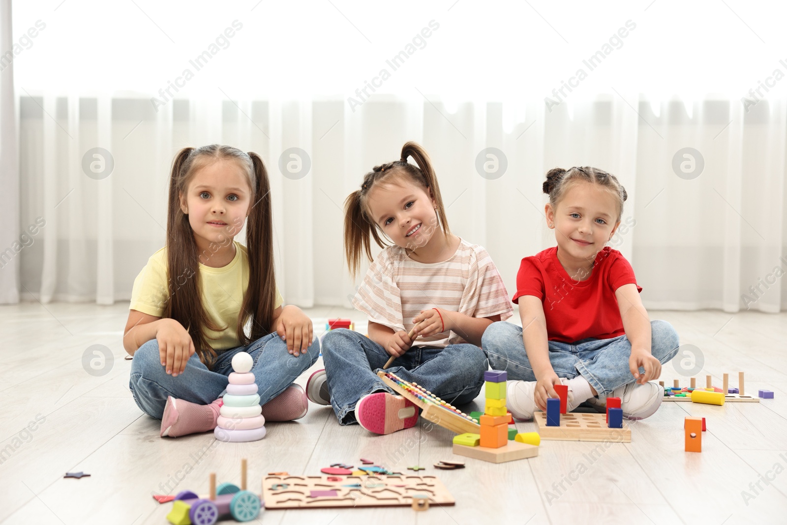 Photo of Cute little children playing together on floor indoors