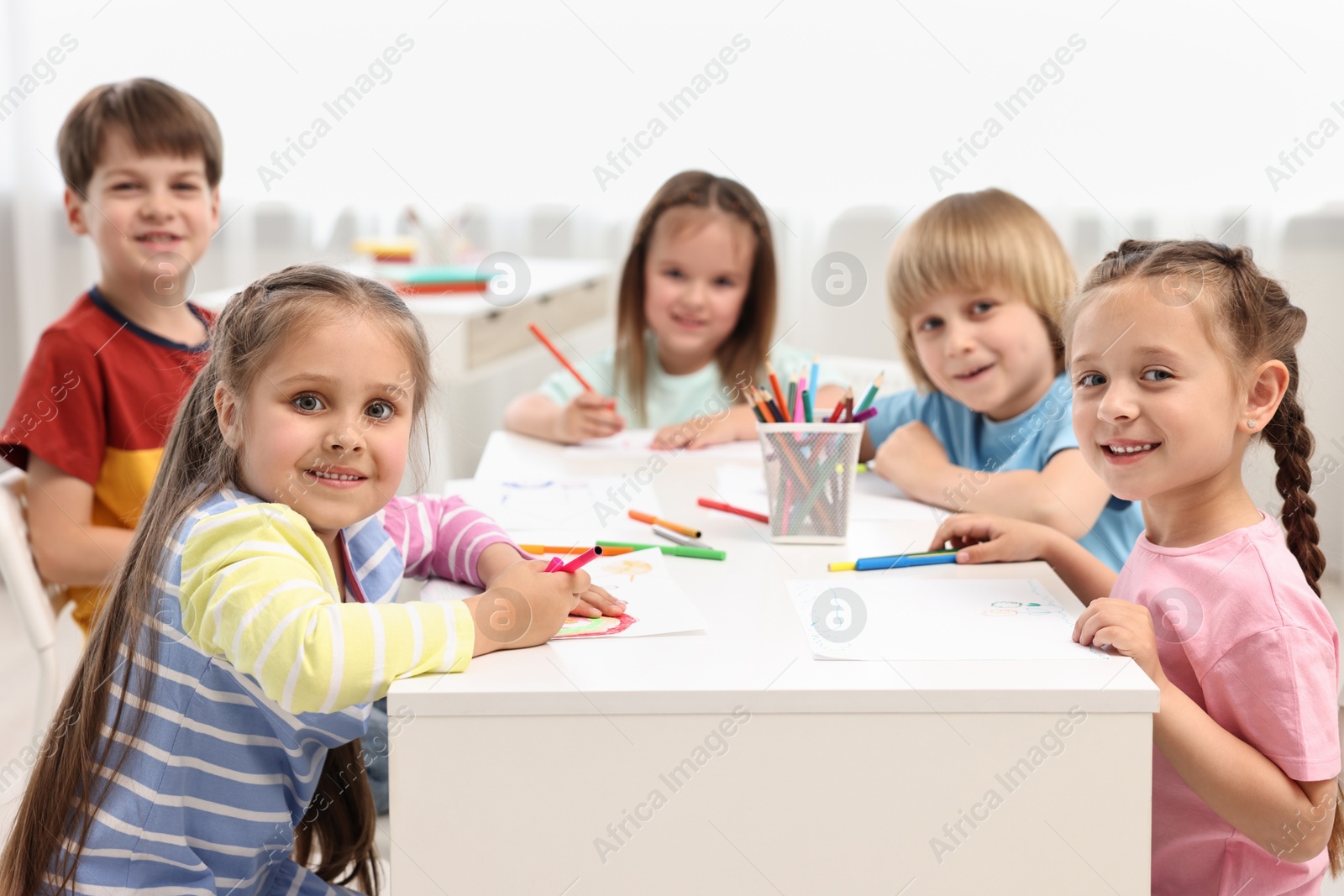 Photo of Group of children drawing at table indoors